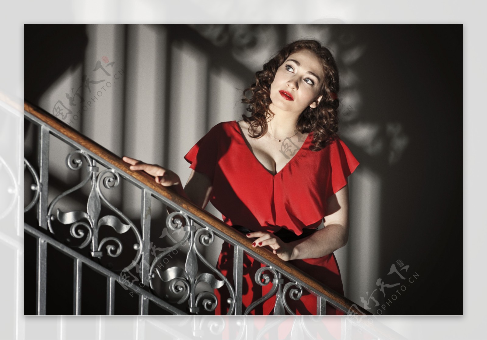 站在楼梯上手扶栏杆穿红色上衣的美女图片