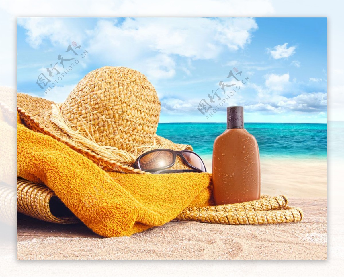 沙滩上的帽子防晒油和眼镜图片