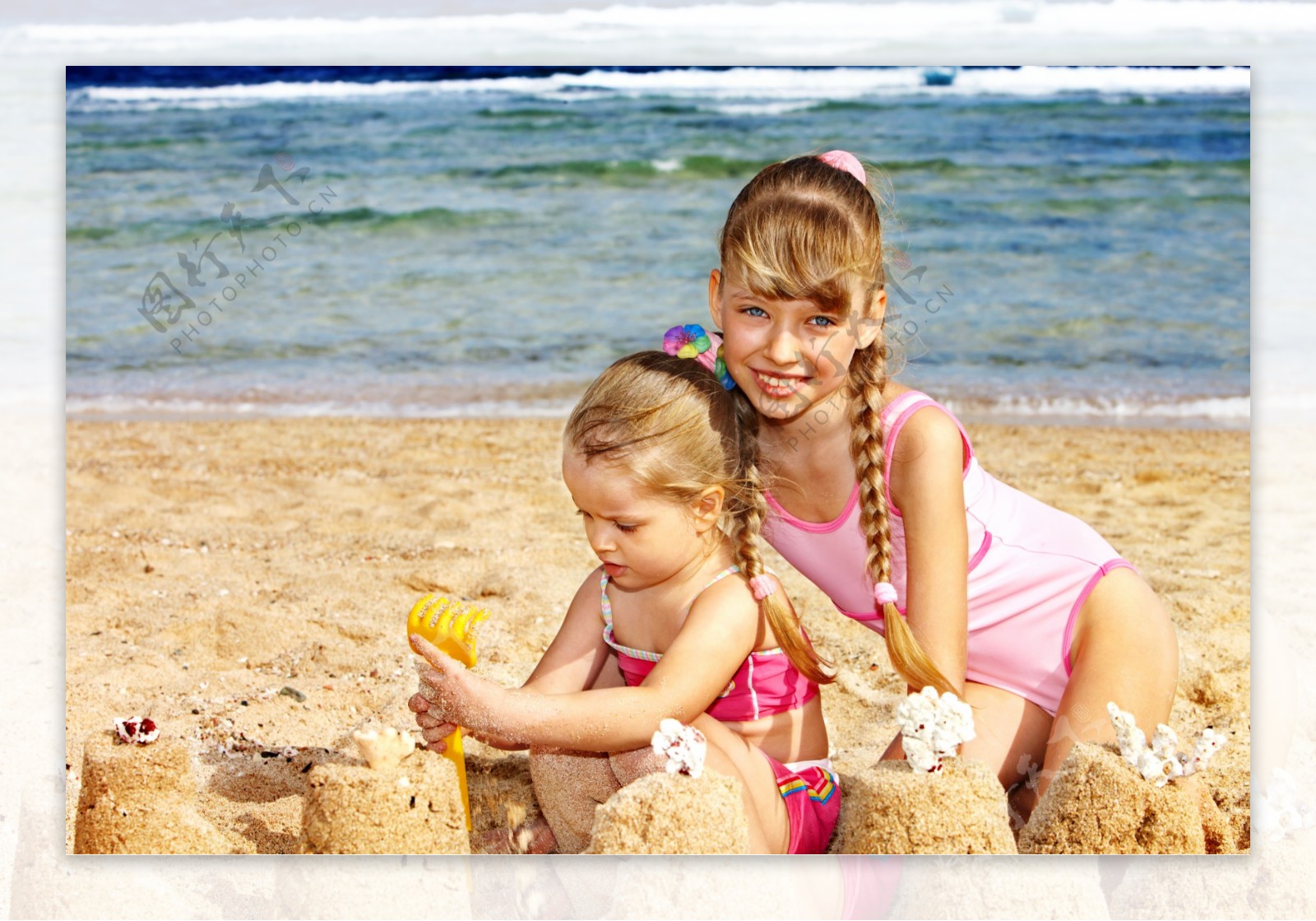 沙滩上玩沙的两个小女孩图片