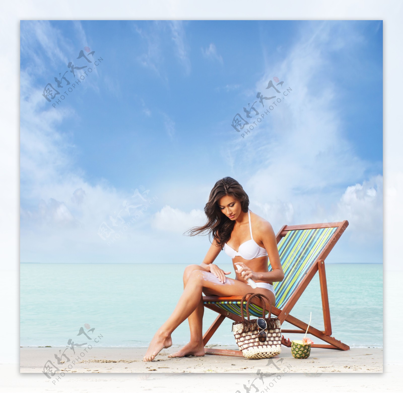 沙滩上涂抹防晒霜的女人图片