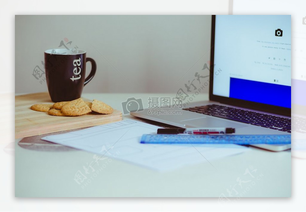 表上的笔记本电脑蓝色统治者杯和Cookies