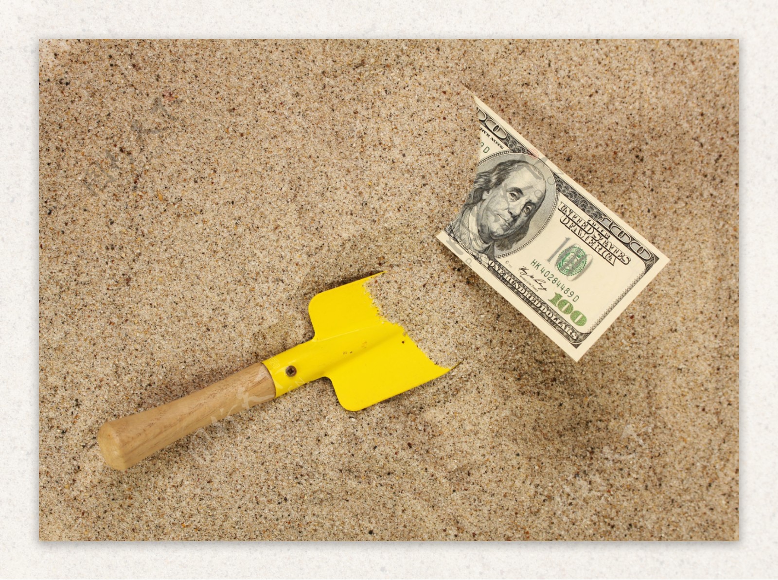 沙子里的美元与铲子图片