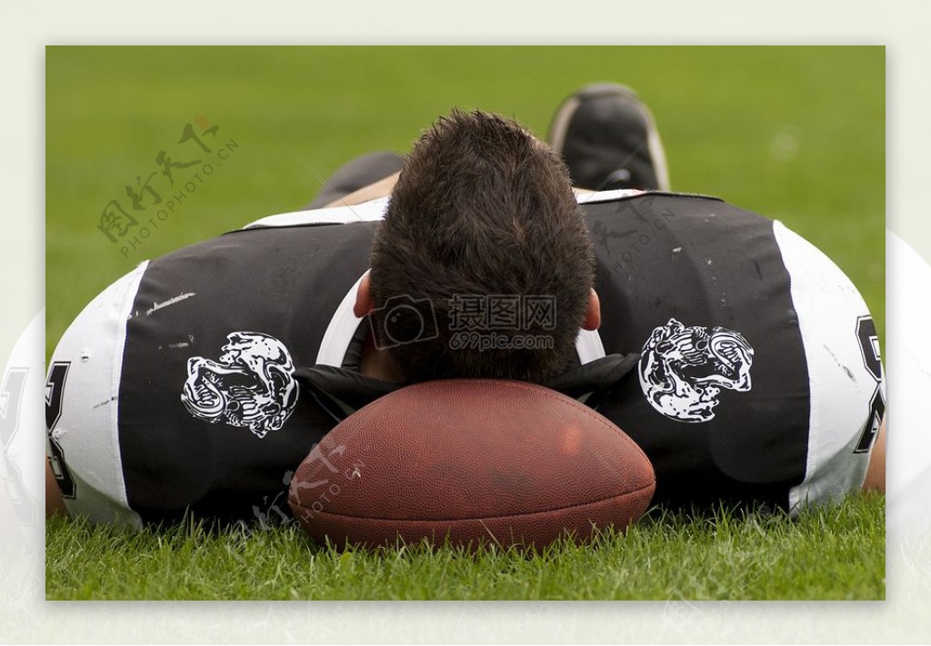 一个运动员头枕在橄榄球上