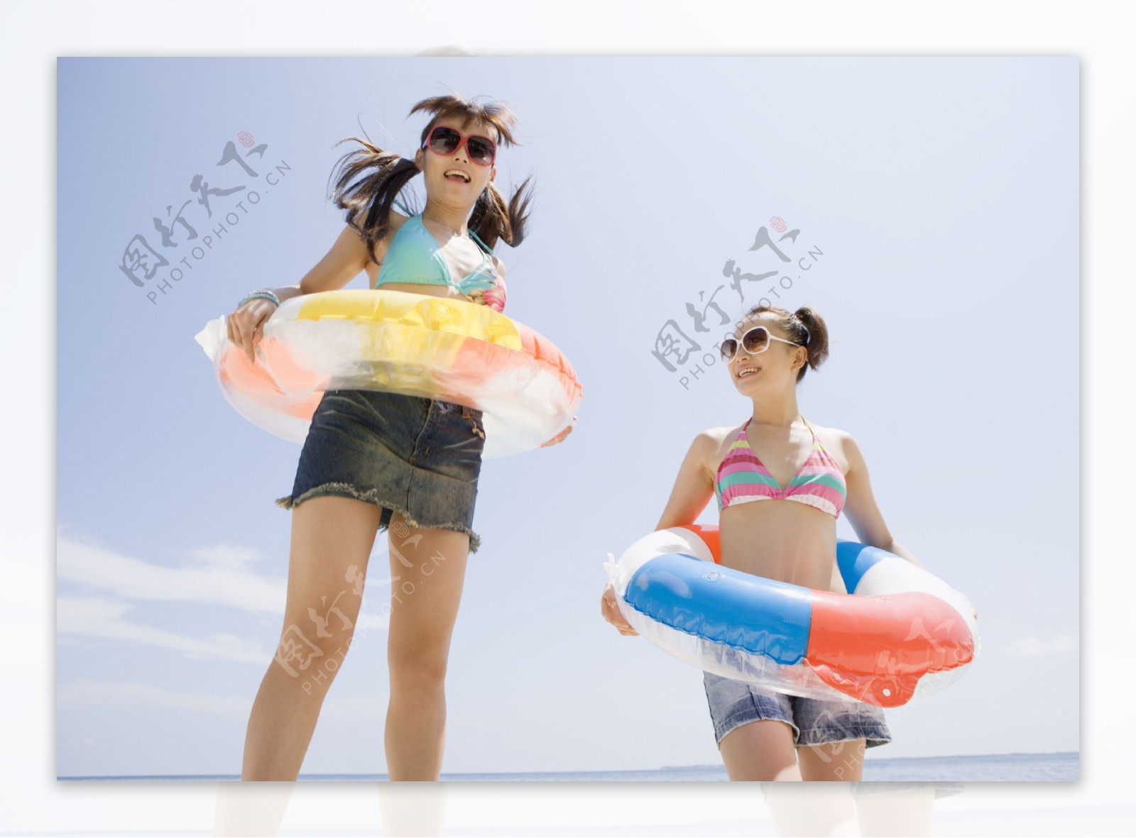 沙滩上戴太阳镜套游泳圈的美少女图片