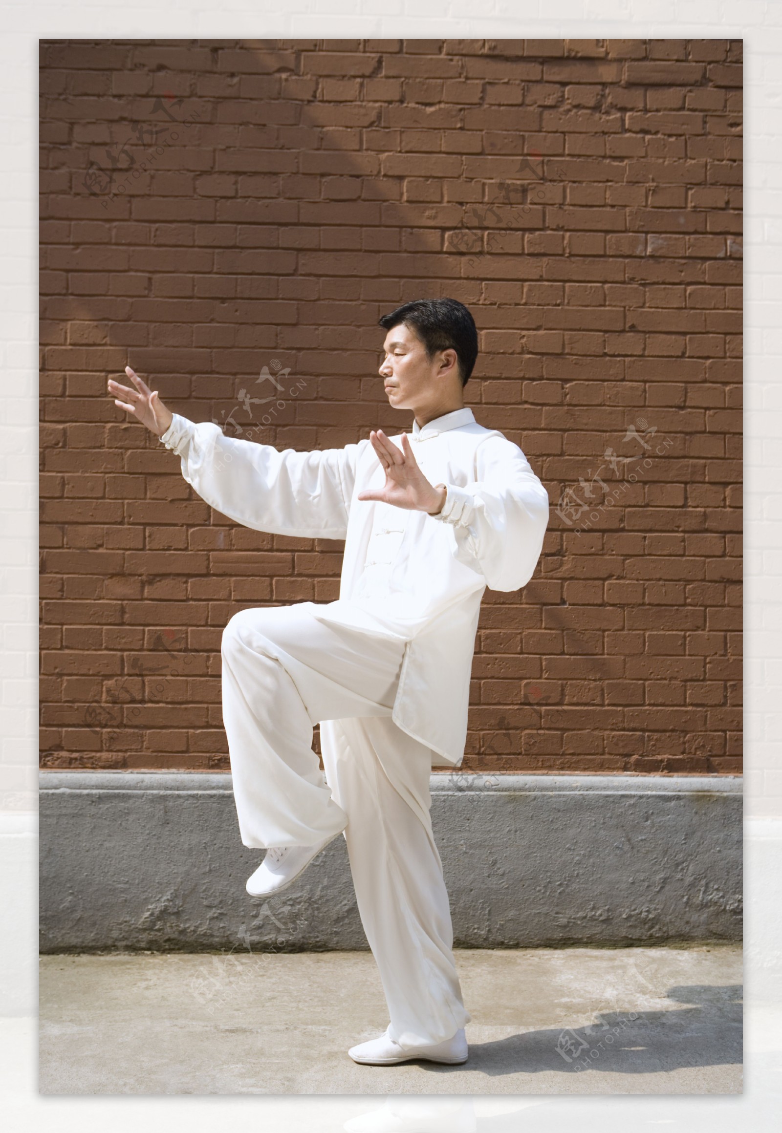 砖墙旁练太极拳的中年师傅图片
