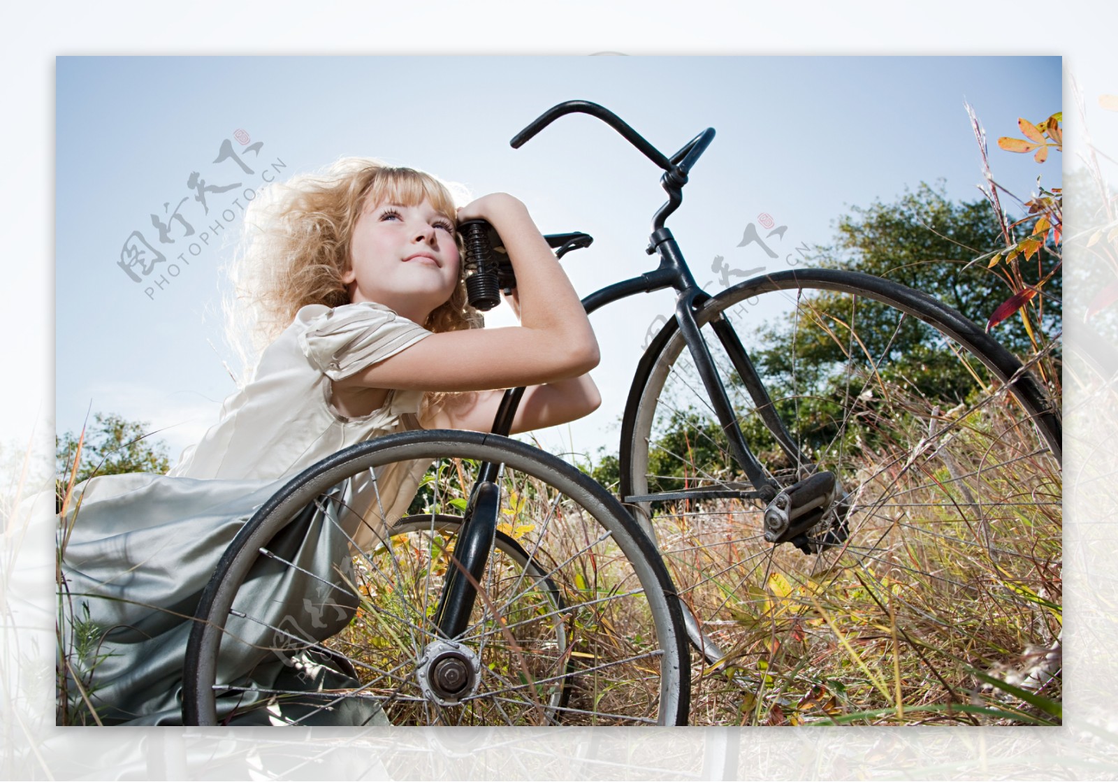 草丛中趴着自行车上的小女孩图片