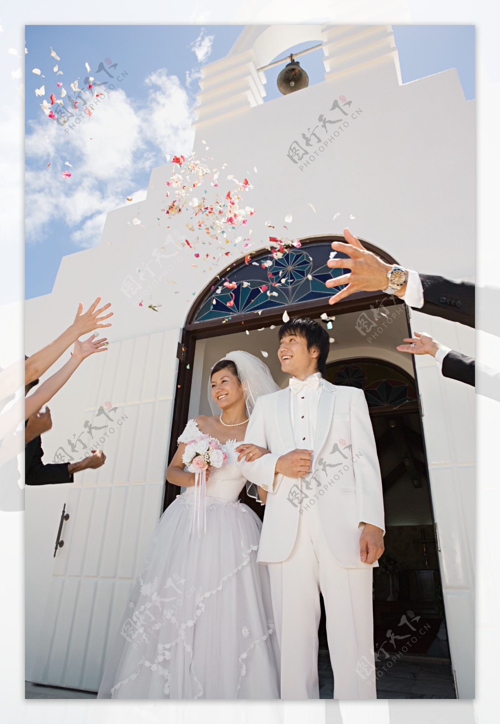 礼堂前看着飘落花瓣幸福微笑的新郎新娘图片图片